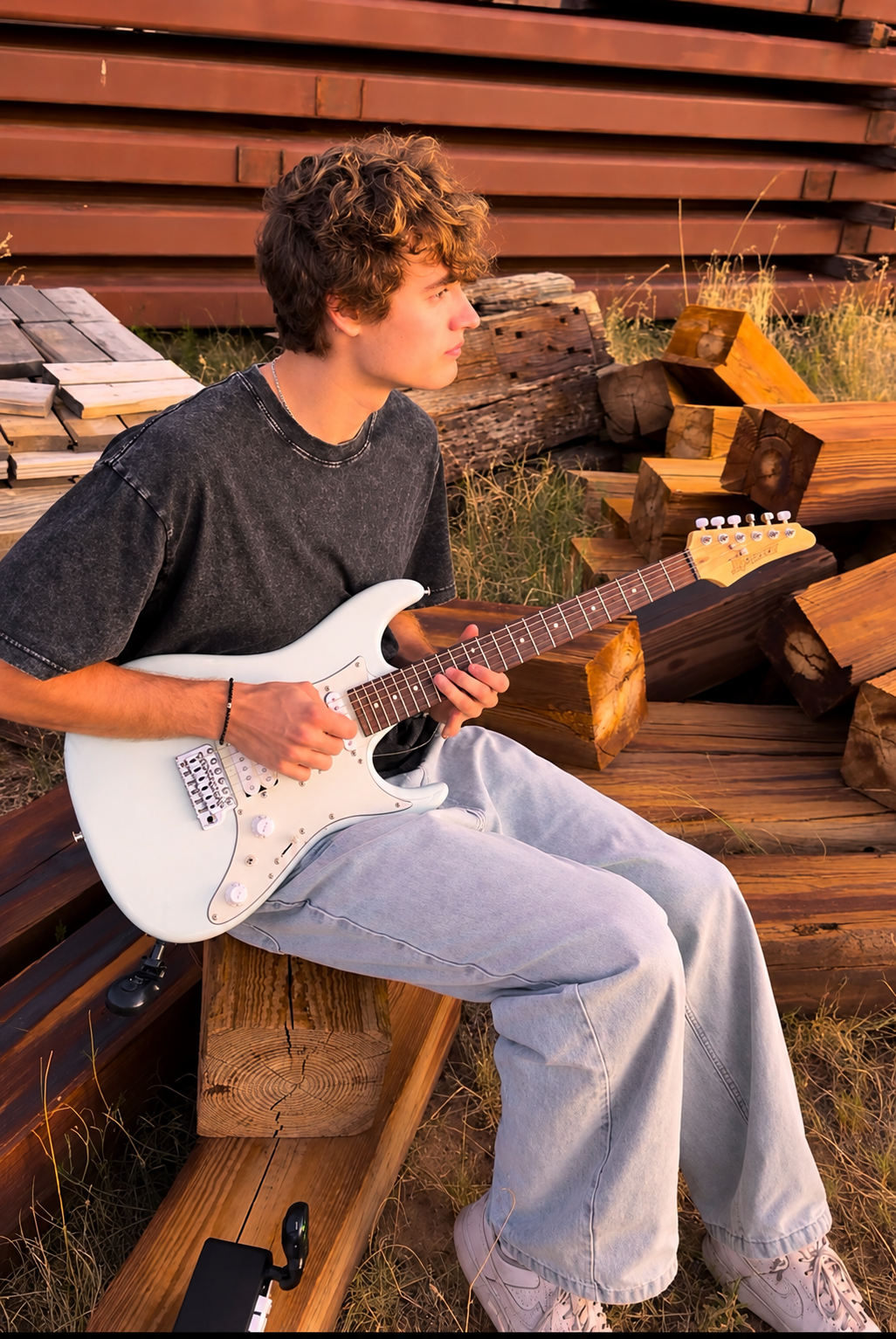Christian seated with his white electric guitar in warm evening light